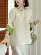 Model wearing an ivory silk top with Chinese-inspired detailing and contrasting green cuffs