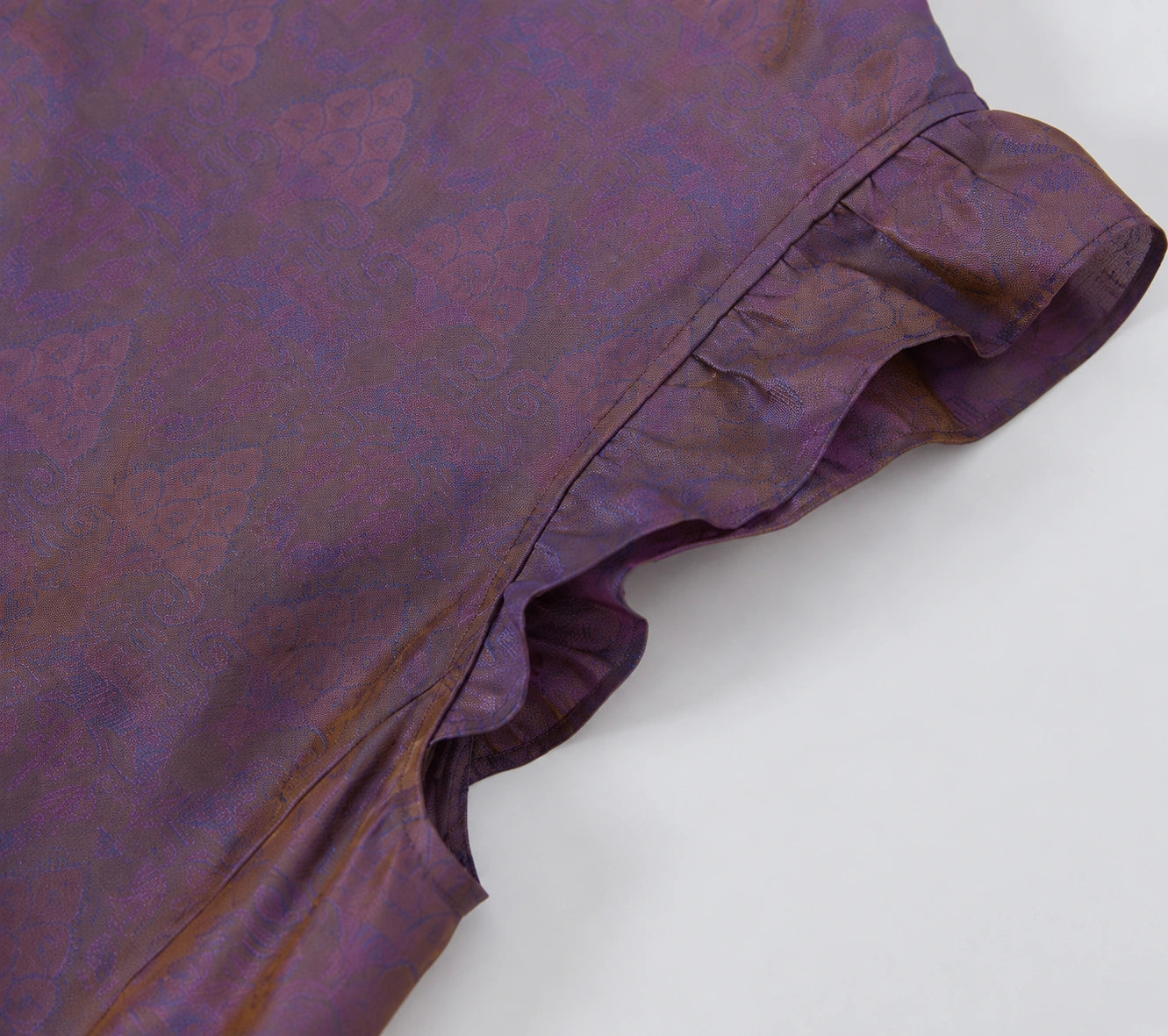 Close-up of the ruffled flutter sleeve and tone-on-tone jacquard pattern on luminous silk fabric.