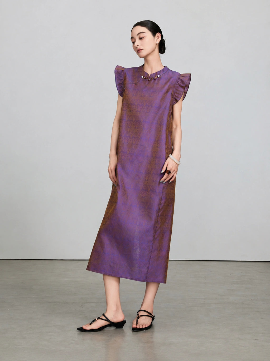 Side view of a woman wearing a luminous purple and bronze silk qipao-inspired midi dress.