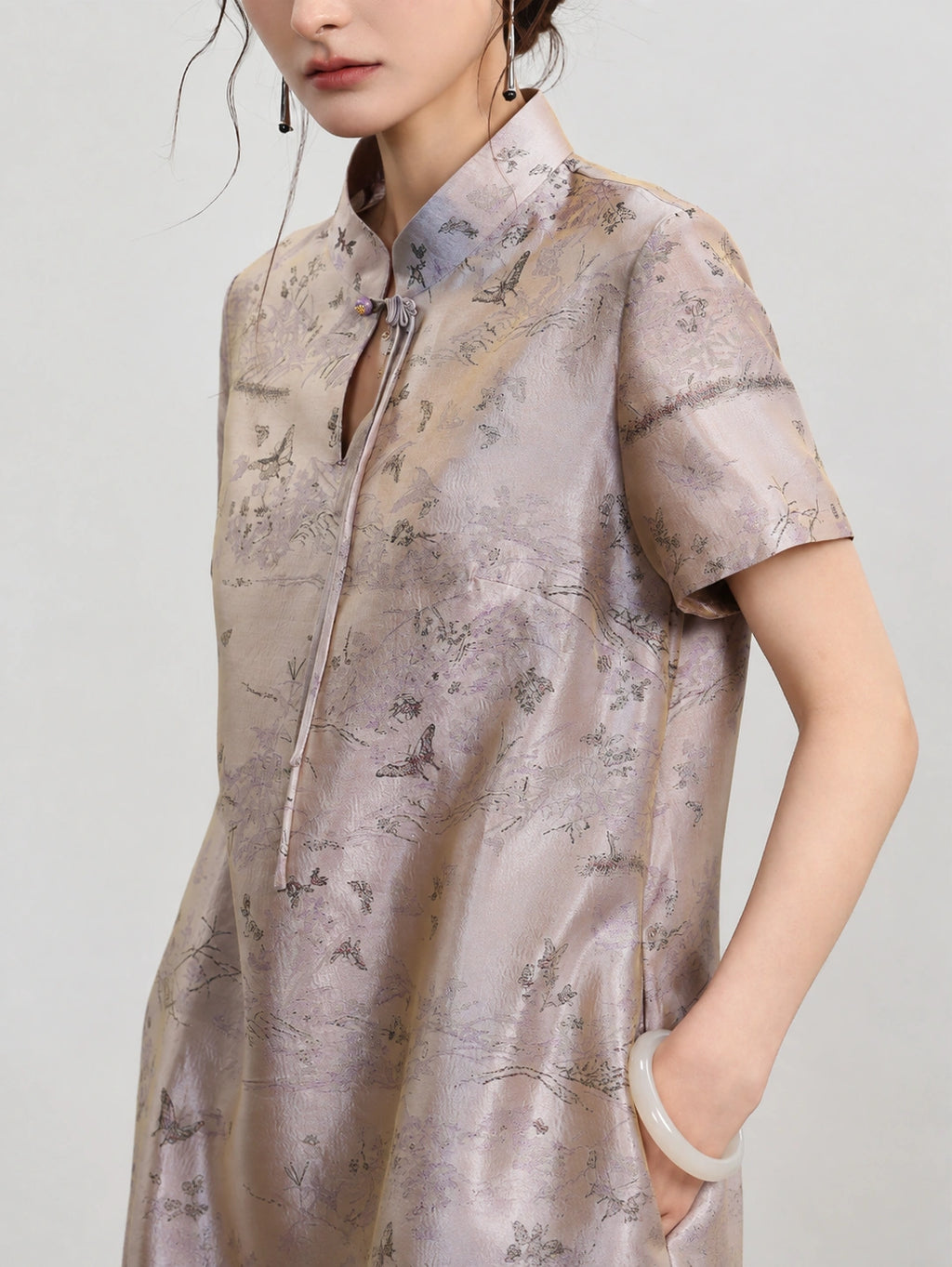 Upper-body view of the luminous scenic jacquard, stand collar and ornamental knot closure