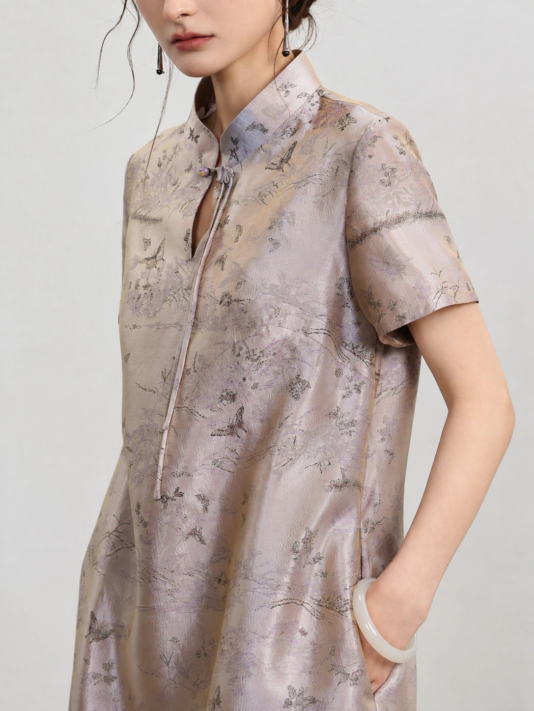 Upper-body view of the luminous scenic jacquard, stand collar and ornamental knot closure