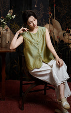 Front seated view of the celadon-and-gold silk vest with decorative green buttons