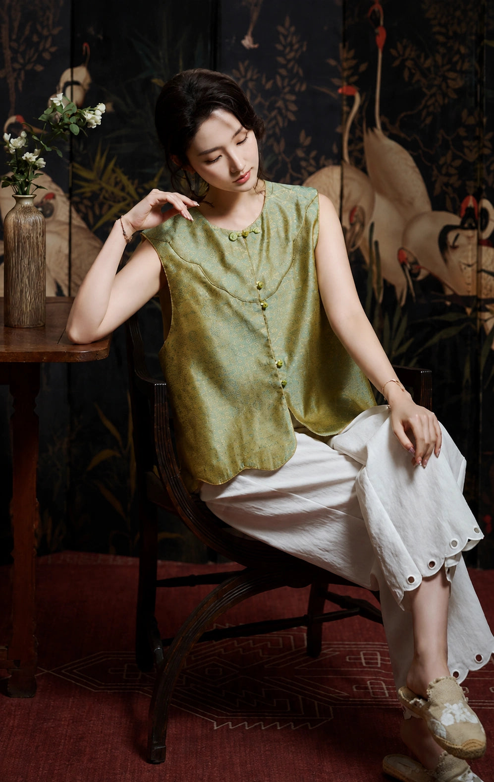 Front seated view of the celadon-and-gold silk vest with decorative green buttons