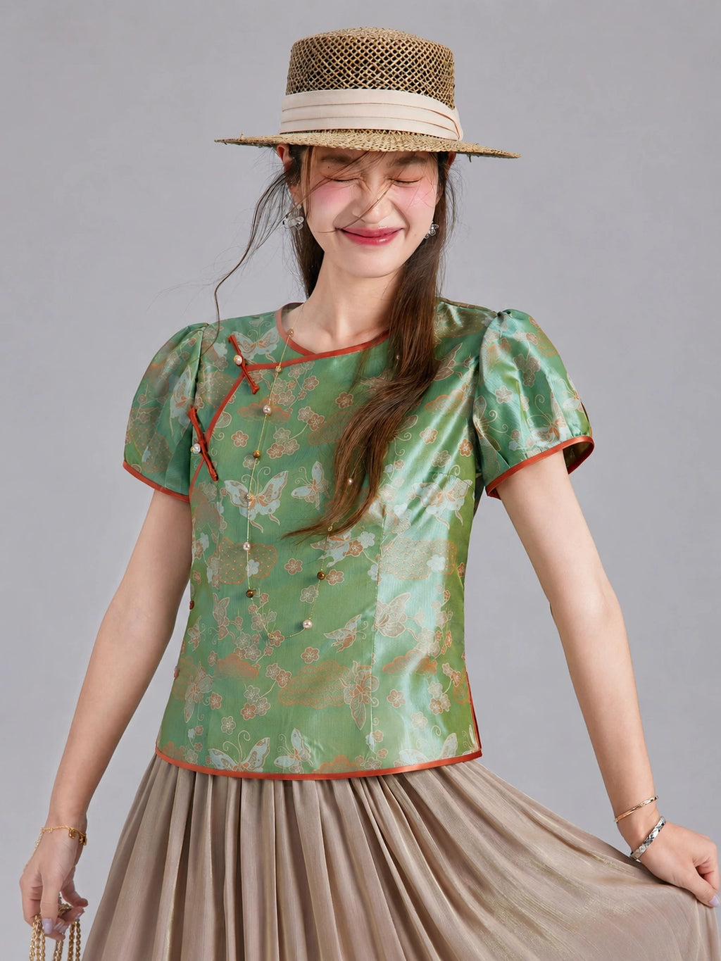 Front view of a Gambiered Silk jade green brocade top with a round neckline, decorative buttons and shaped seams