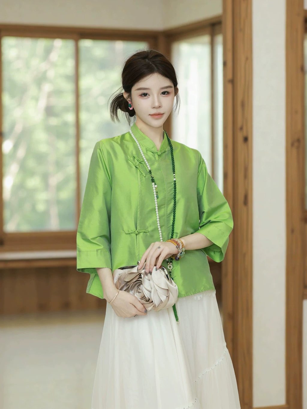 Model wearing a jade green Chinese-inspired silk top with straight sleeves and traditional closures