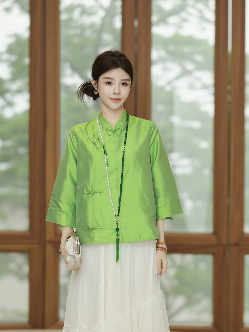 Front view of a model wearing a jade green mid-length silk top with a mandarin-style collar
