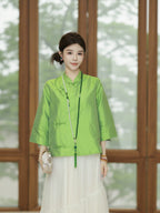 Front view of a model wearing a jade green mid-length silk top with a mandarin-style collar