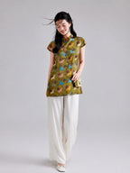 Model wearing a Gambiered Silk olive-gold rayon longline top with colorful rabbits and botanical motifs