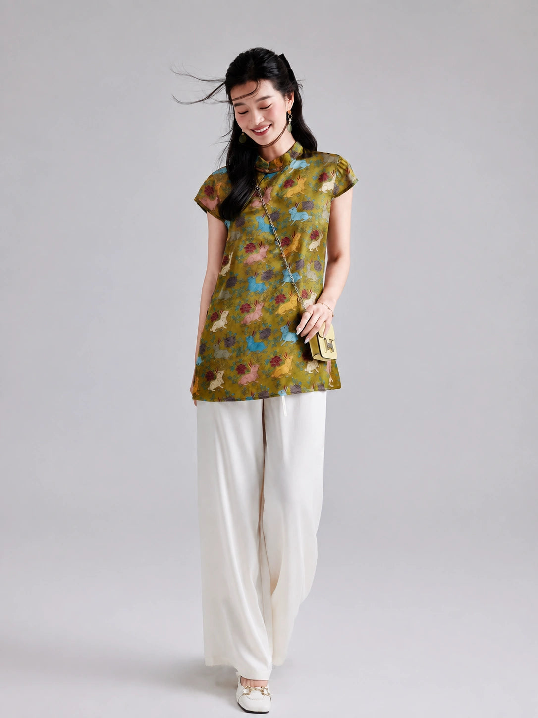 Model wearing a Gambiered Silk olive-gold rayon longline top with colorful rabbits and botanical motifs