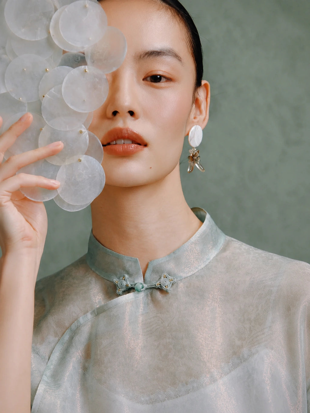 Close-up of the Mandarin collar and handcrafted frog button on the light celadon silk cheongsam top by Gambiered Silk.