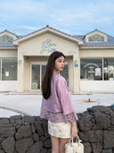Back view of a rose pink silk jacket with openwork hem and straight sleeves