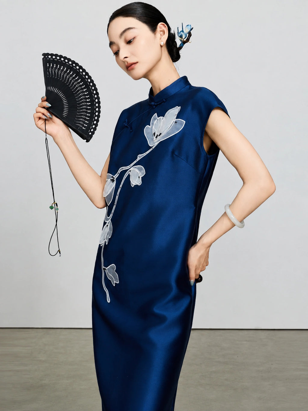 Close view of the white magnolia embroidery and lustrous navy fabric on the qipao dress