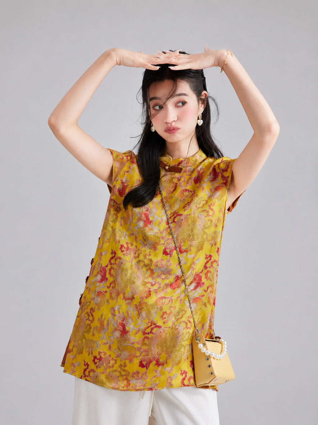 Front view of a relaxed golden longline top with a Mandarin collar, side button details and colorful motifs