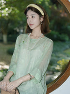 Close-up of the mint green silk top showing its botanical texture and diagonal closure