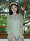 Model wearing a mint green textured silk top styled with layered pearl necklaces