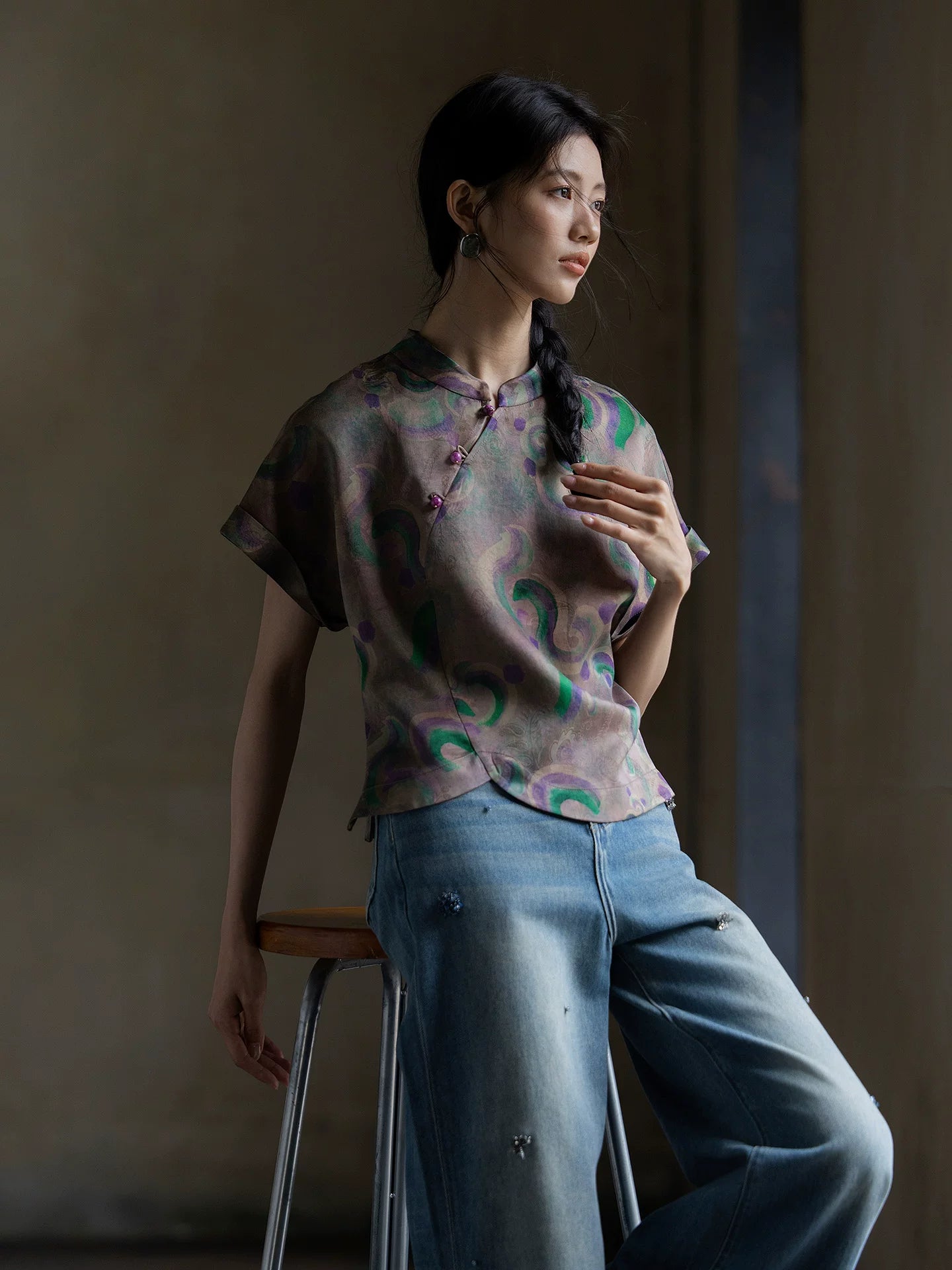 Side view of a modern oriental Gambiered Silk blouse paired with light blue denim jeans.