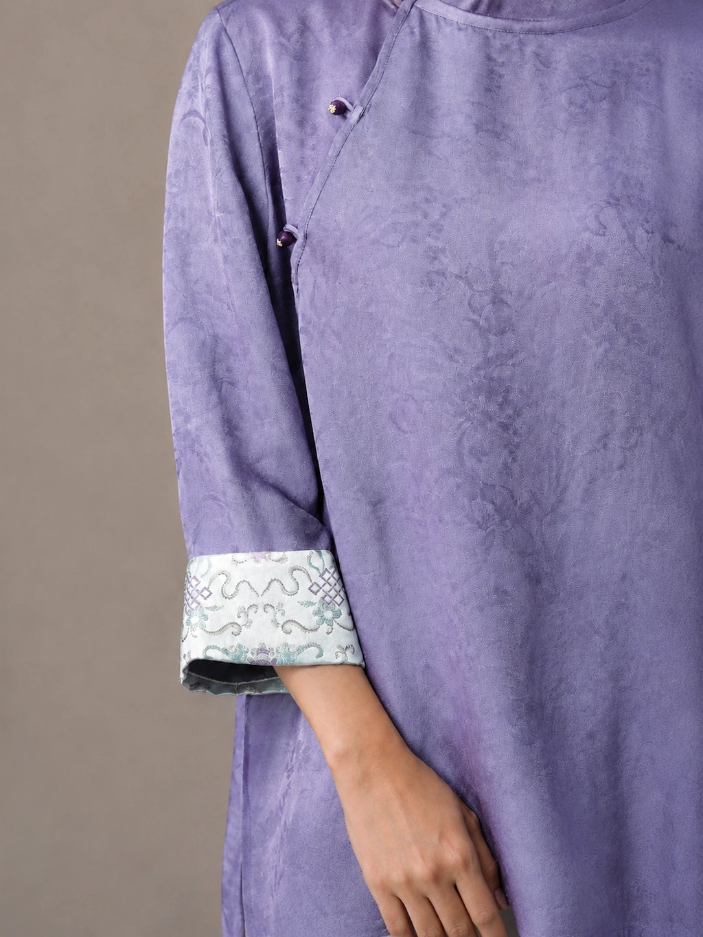 Close-up of lilac viscose and mulberry silk blouse cuff with traditional Chinese pattern.