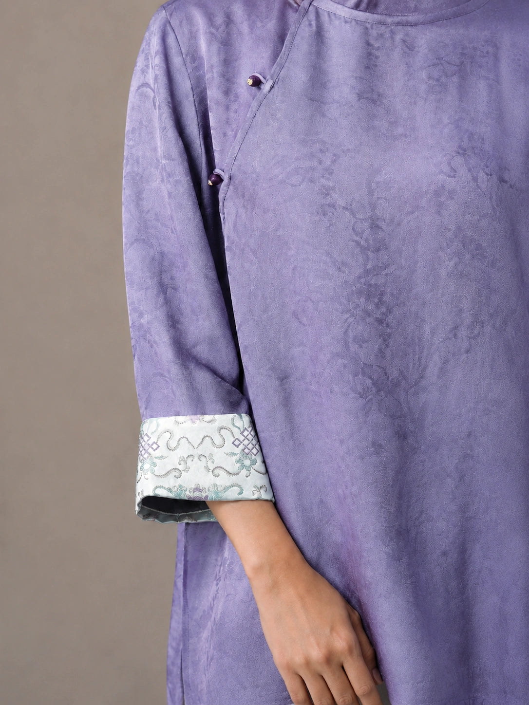 Close-up of lilac viscose and mulberry silk blouse cuff with traditional Chinese pattern.