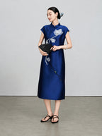 Model styling the navy embroidered cheongsam dress with a traditional black folding fan