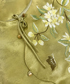 Close-up of floral and butterfly embroidery with knotted tie and bead-style closures