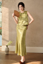 Model holding a wooden fan while wearing the olive rayon-linen jacquard vest