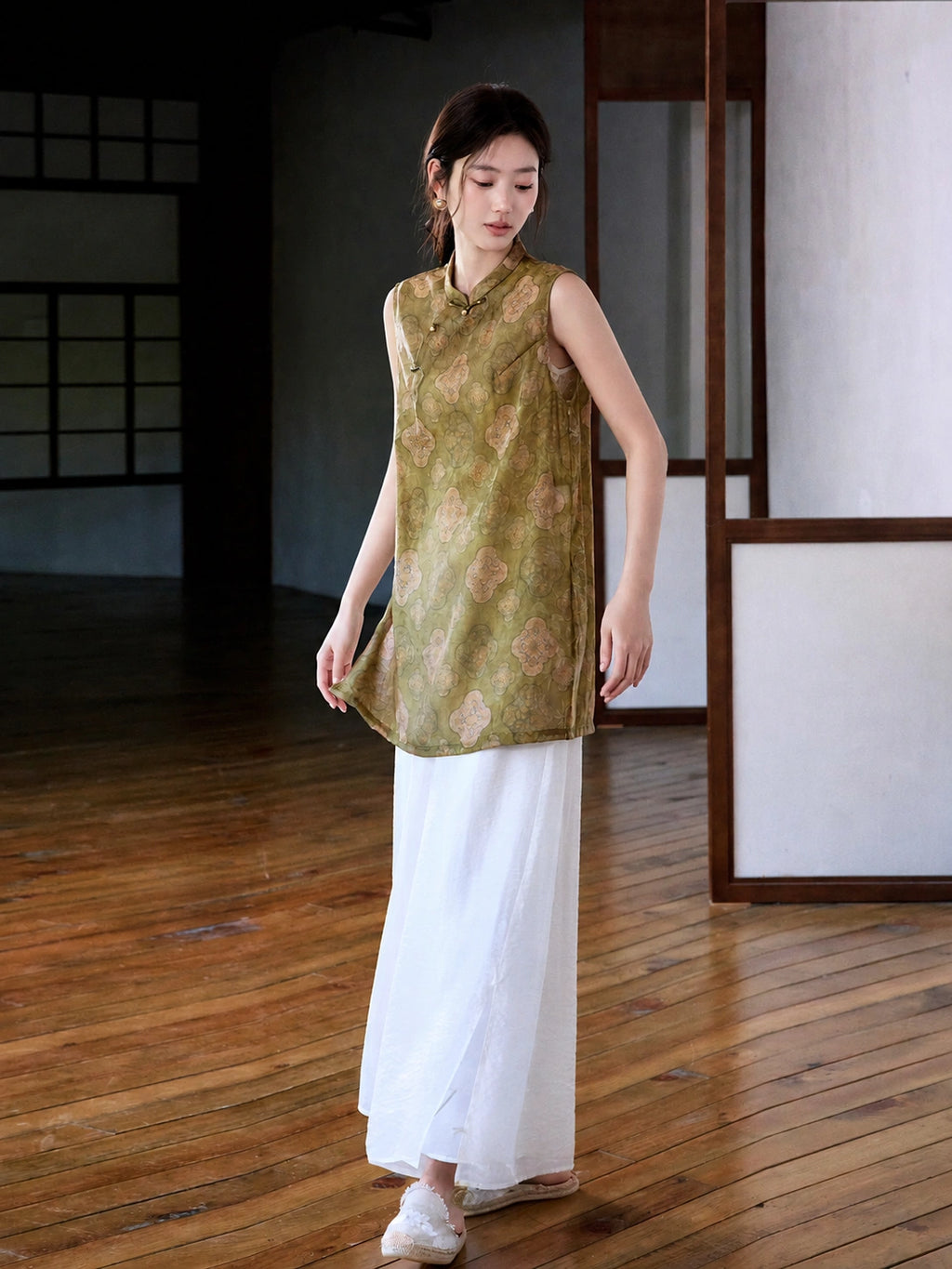 Side view of relaxed olive medallion jacquard vest paired with flowing white trousers