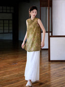 Side view of relaxed olive medallion jacquard vest paired with flowing white trousers