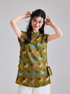 Model wearing an olive-gold Gambiered Silk top with blue, pink, yellow and ivory rabbits among flowers