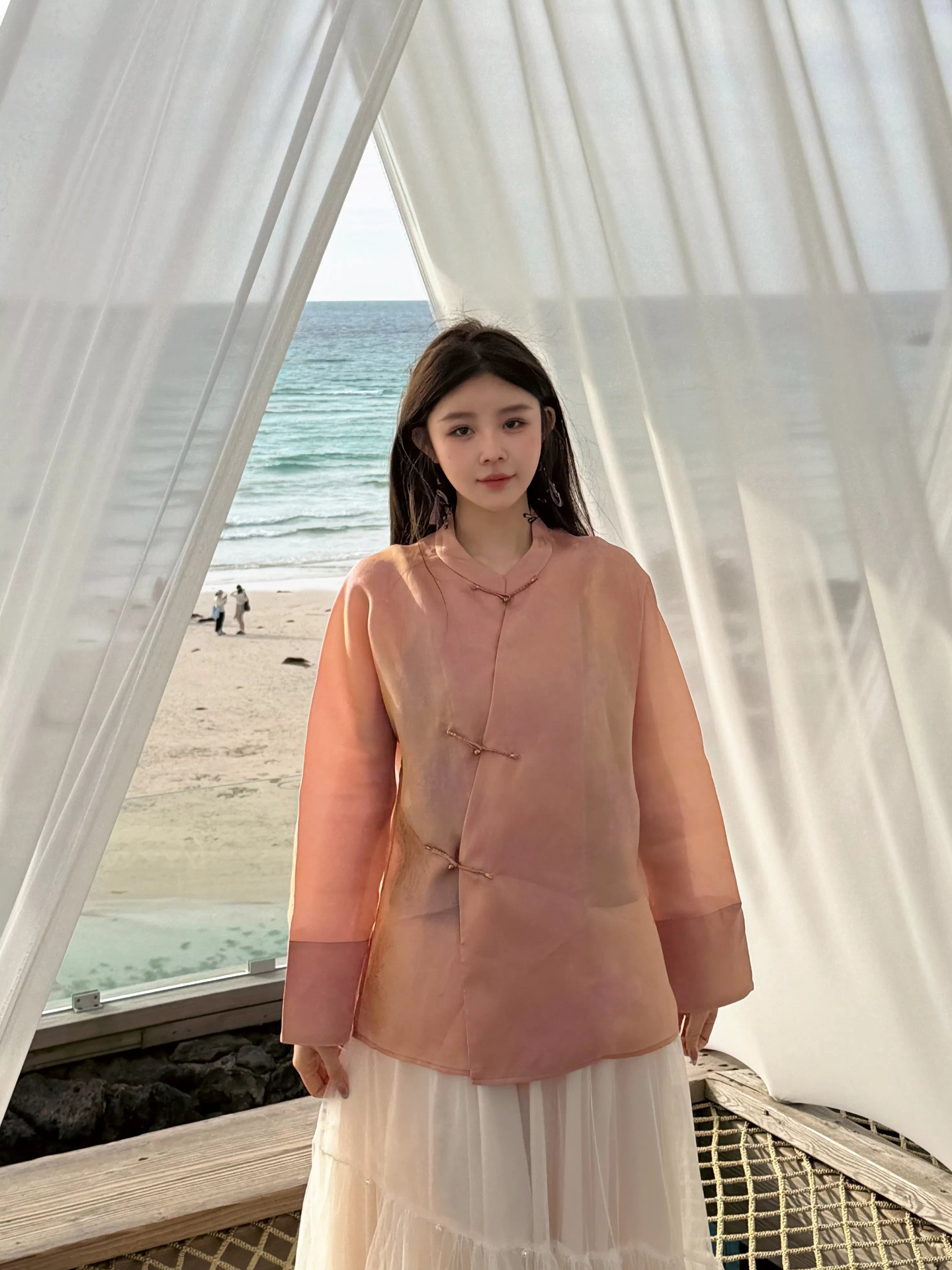 Model wearing a lightweight peach pink mulberry silk top with long straight sleeves