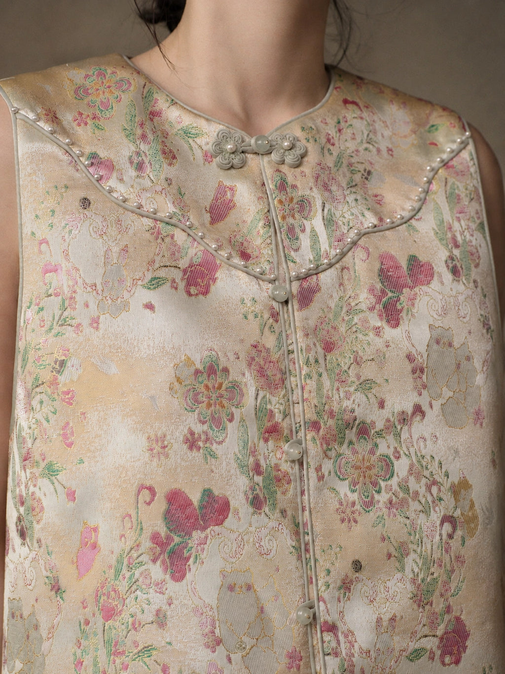 Close-up of the floral jacquard, pearl-like trim, contrast piping and decorative frog buttons