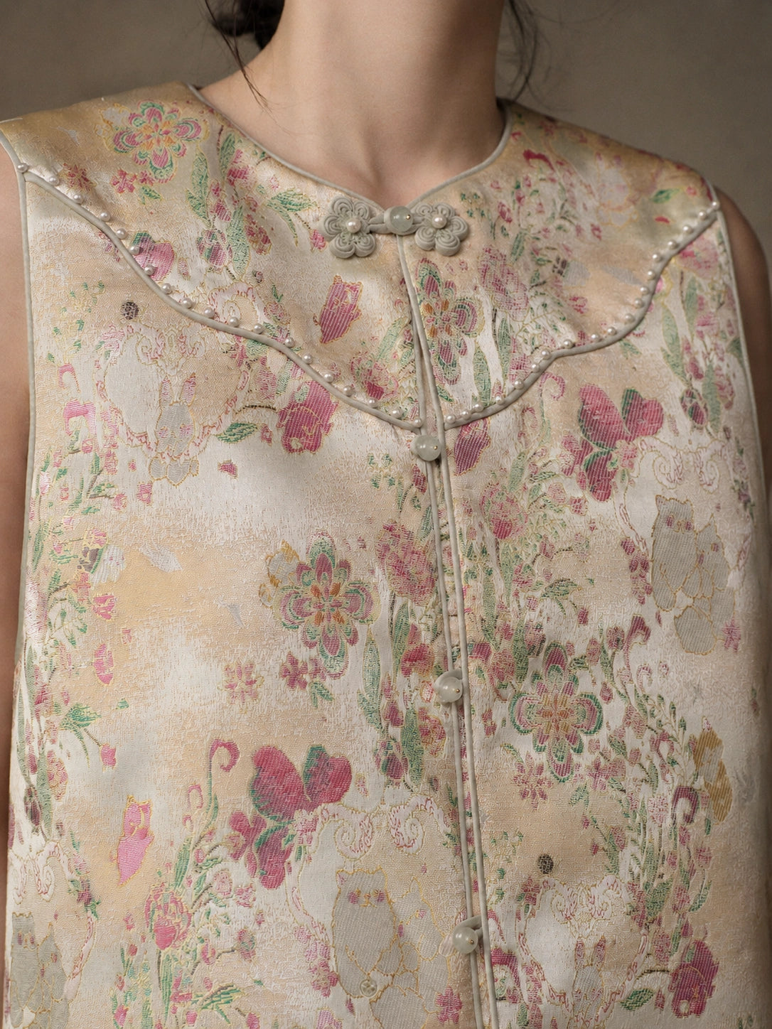Close-up of the floral jacquard, pearl-like trim, contrast piping and decorative frog buttons