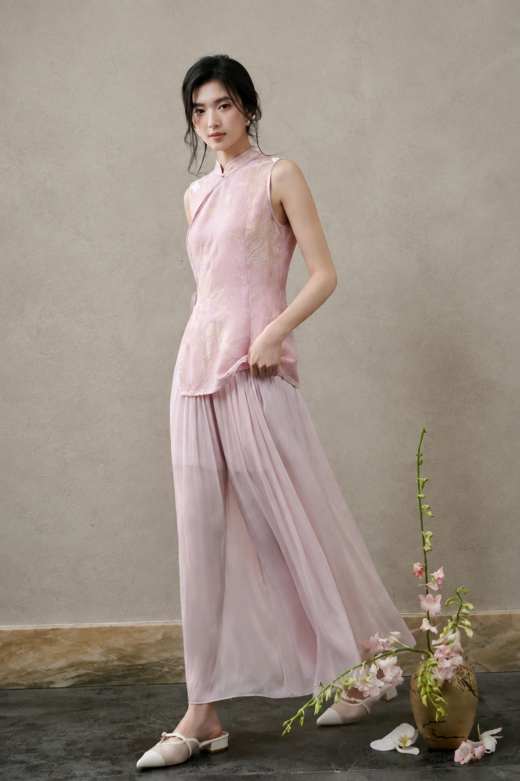 Model wearing a blush-pink silk-rich cut-velvet Mandarin vest with flowing pink trousers