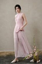 Model wearing a blush-pink silk-rich cut-velvet Mandarin vest with flowing pink trousers