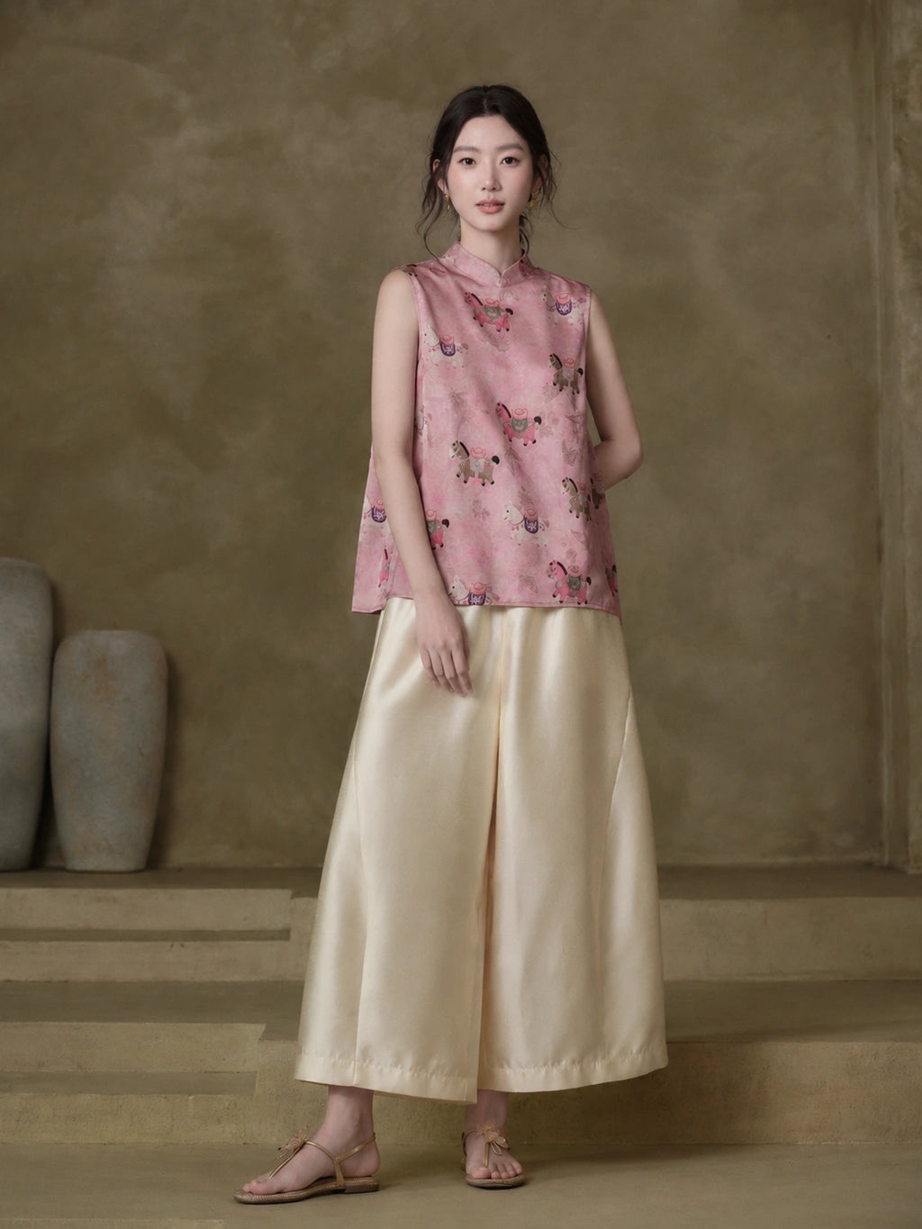 Model wearing the Gambiered Silk dusty pink horse-motif jacquard vest with ivory wide-leg trousers