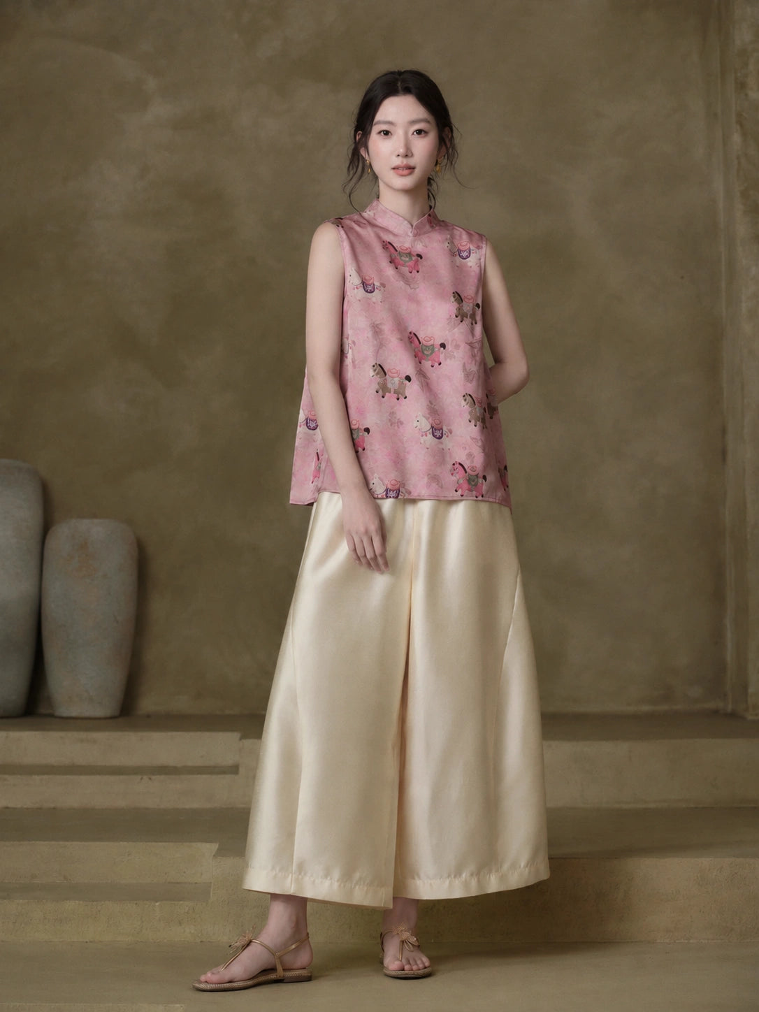 Model wearing the Gambiered Silk dusty pink horse-motif jacquard vest with ivory wide-leg trousers