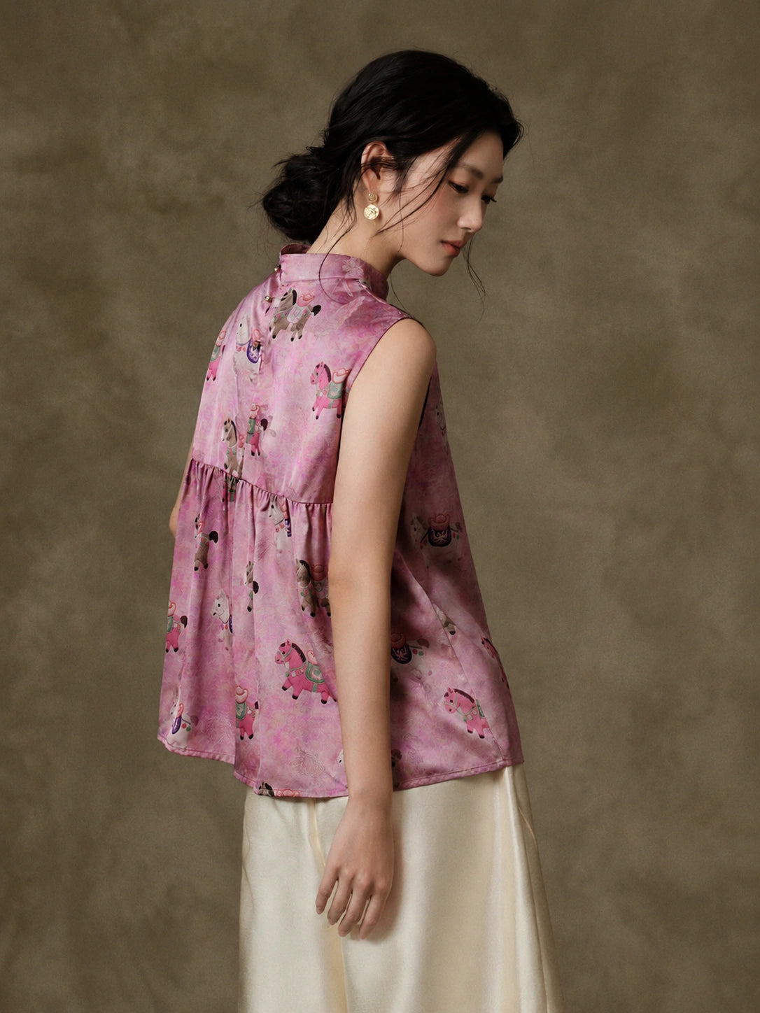 Back three-quarter view showing the softly gathered panel and relaxed silhouette of the pink vest
