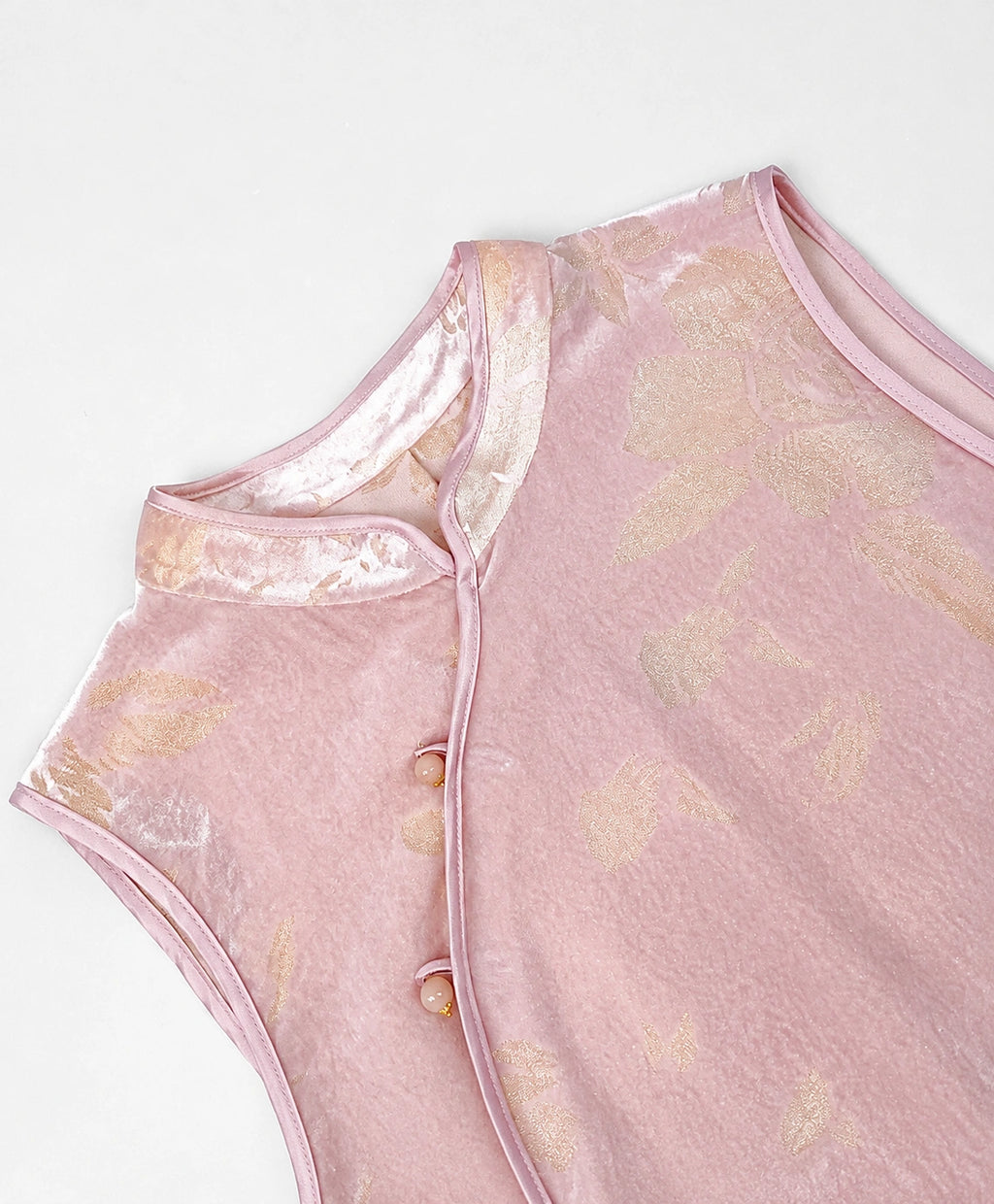 Blush-pink cut-velvet vest showing its Mandarin collar, asymmetric piping and decorative frog-button closures