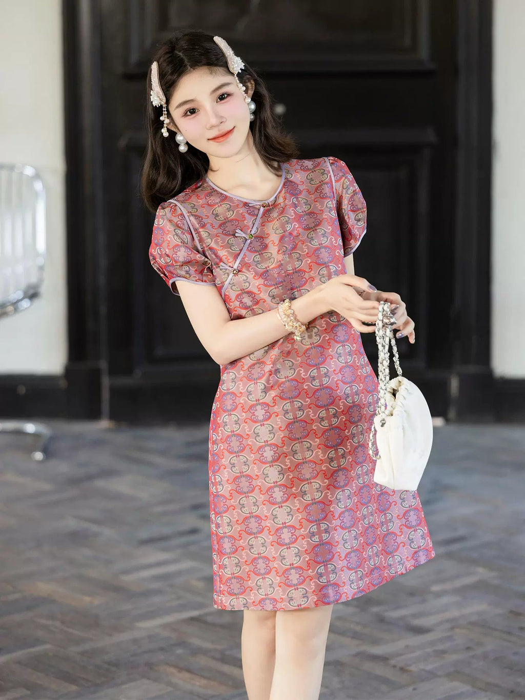 Model wearing a pink 100% mulberry silk Chinese-style dress with a traditional-inspired pattern and short puff sleeves.