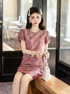 Close-up view of a model wearing a pink mulberry silk dress with Chinese knot closures and a traditional-inspired pattern.