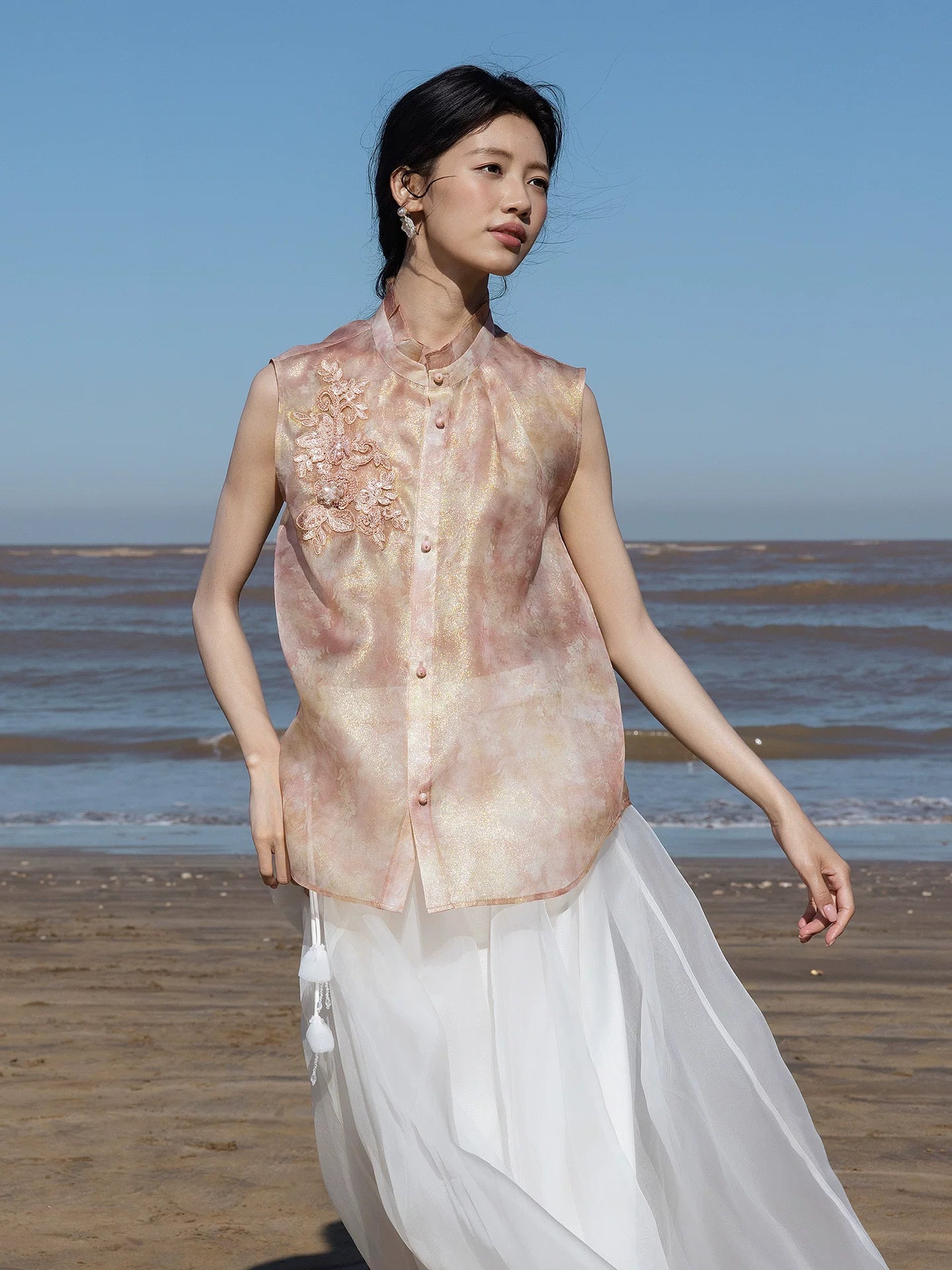 Model wearing a blush pink mulberry silk sleeveless embroidered top paired with a flowing white skirt.