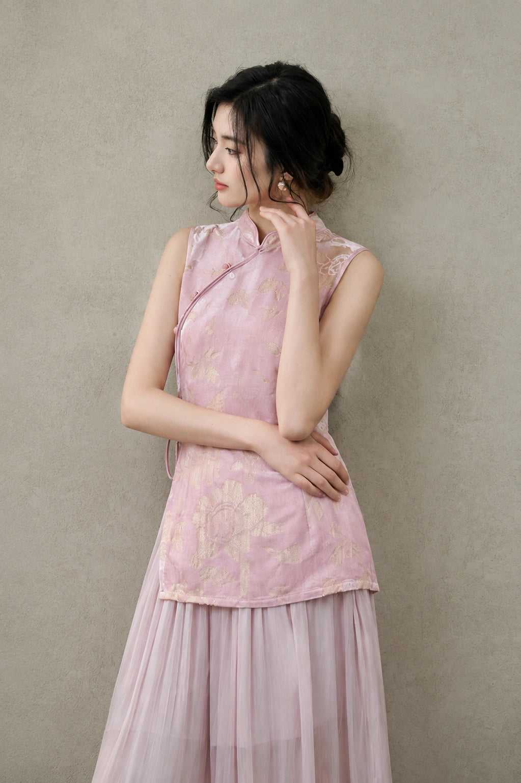 Portrait of a model wearing a blush-pink Mandarin-collar vest with lustrous champagne floral patterns