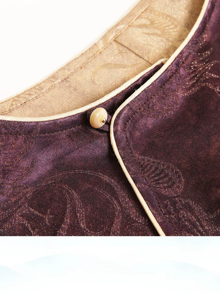 Close-up of a plum Chinese-inspired silk-blend top showing the diagonal front closure and gold piping