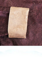 Close-up of a plum silk-blend top with a contrasting champagne cuff and tonal pattern