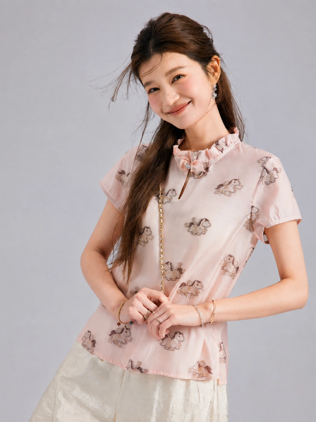 Front view of a blush pink Gambiered Silk top with pony motifs, short sleeves and a ruffle-trimmed neckline