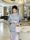 Model wearing a powder blue floral mulberry silk top with elegant three-quarter sleeves