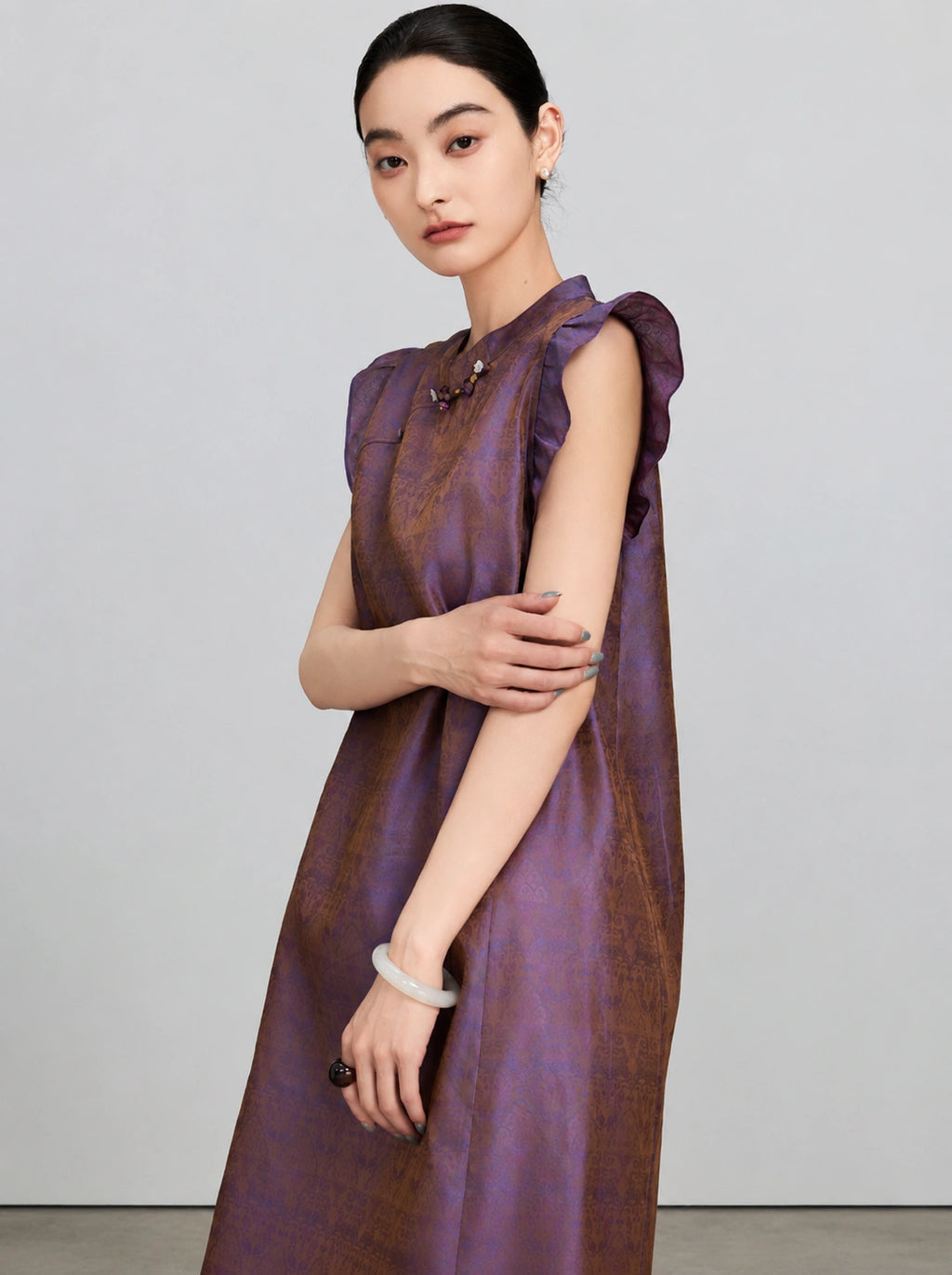Close view of the shimmering purple-bronze jacquard fabric and flutter sleeves on the silk dress.