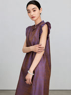 Close view of the shimmering purple-bronze jacquard fabric and flutter sleeves on the silk dress.