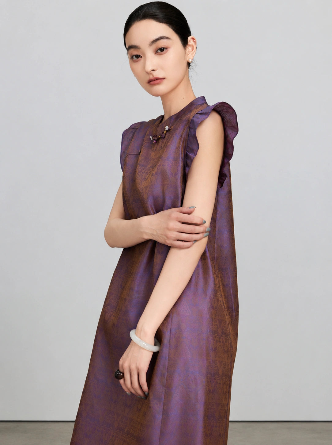 Close view of the shimmering purple-bronze jacquard fabric and flutter sleeves on the silk dress.