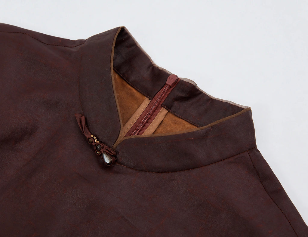 Close-up of the stand collar, gemstone knot closure, contrast piping and concealed back zipper