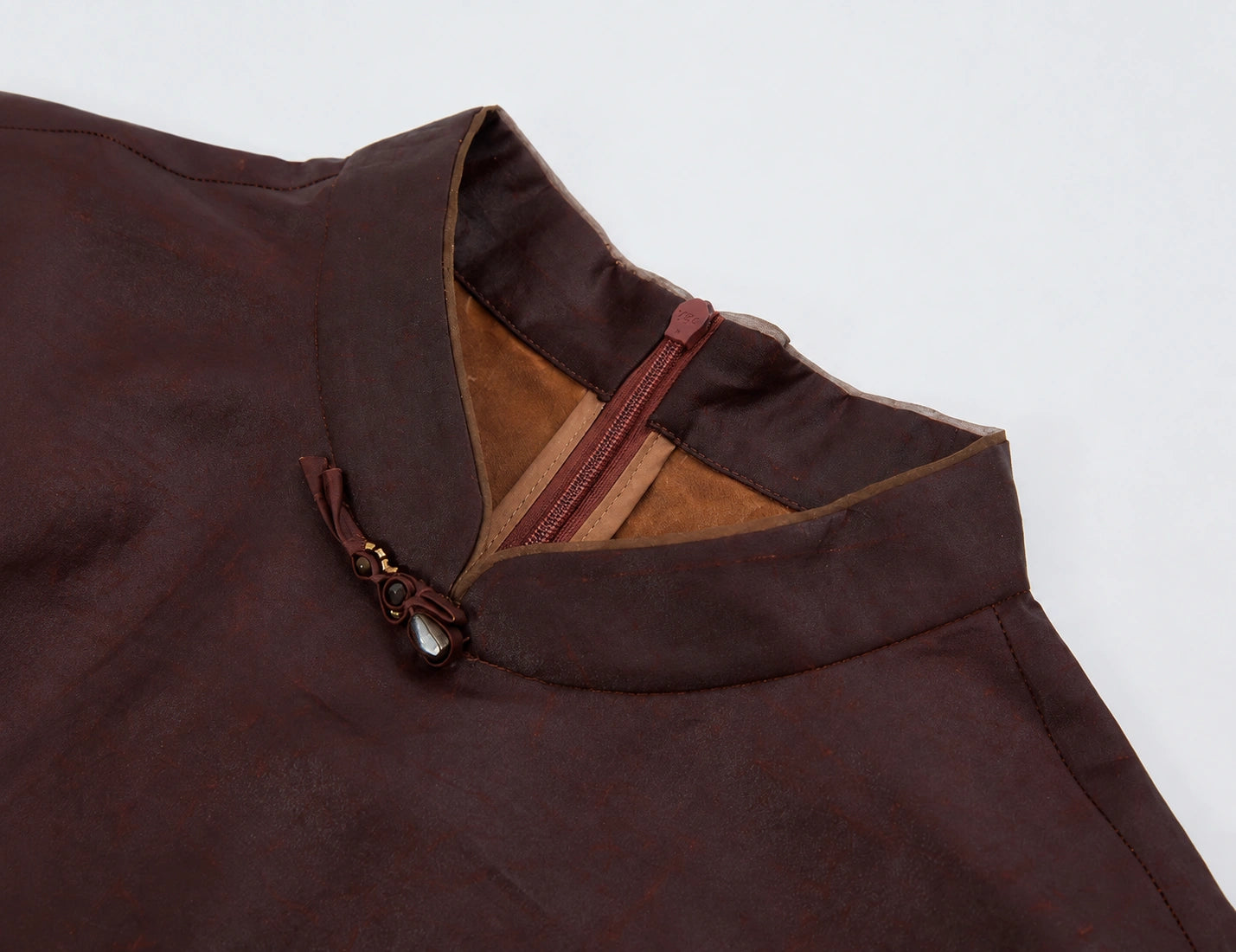 Close-up of the stand collar, gemstone knot closure, contrast piping and concealed back zipper